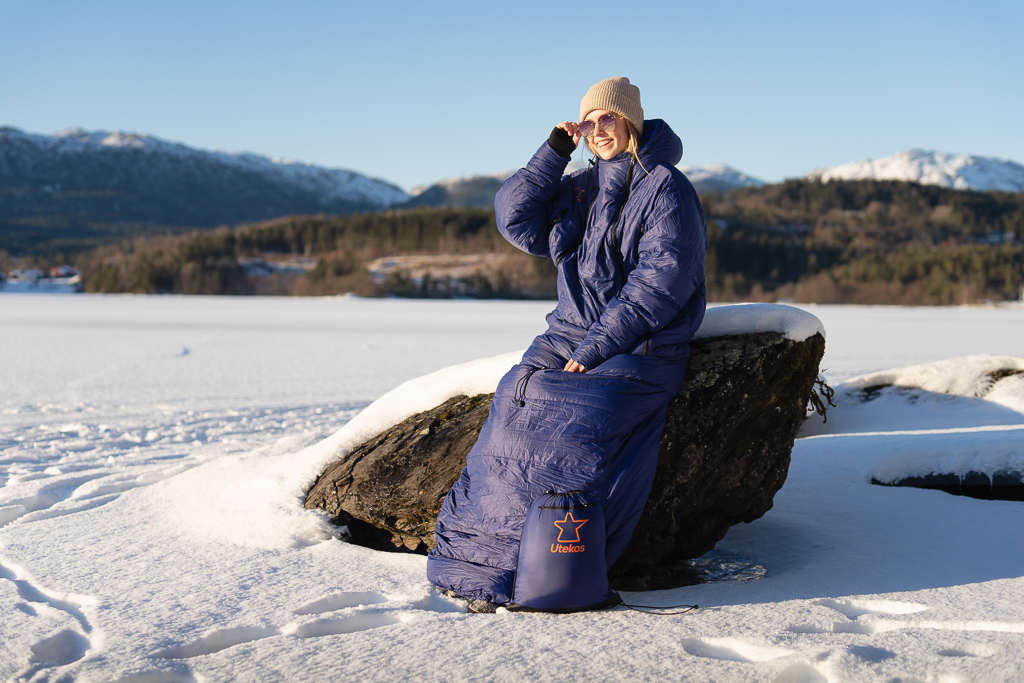 Kvinne med et eksemplar av utekos, som sitter på en stein i solen.